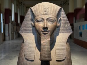 Close view of a granite pharaoh statue wearing a striped nemes headdress and false beard in the Egyptian Museum