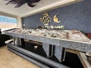 Long decorative fish and shell display beneath a gold fish-and-crescent logo in a Red Sea hotel lobby