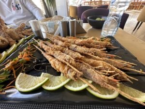 Whole fried fish served on a black platter with lime slices, greens, and shredded vegetables at an Egyptian restaurant