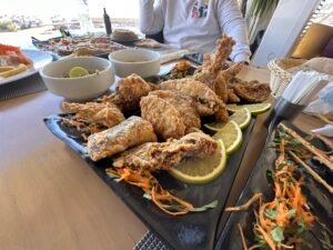 Large pieces of fried fish served on a black platter with lemon slices and shredded vegetables at an Egyptian restaurant
