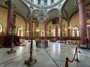 Interior of a historic Coptic church in Coptic Cairo with marble columns, chandeliers, icons, and arched windows