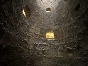 Looking upward inside a tall circular pigeon tower with rough brick walls and small nesting openings