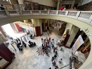 Elevated view across the Egyptian Museum in Cairo with visitors, statues, display cases, and upper galleries