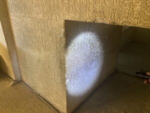 Dense vertical columns of Pyramid Texts carved around a low doorway inside the 5th-Dynasty Pyramid of Unas at Saqqara, Egypt