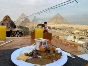Breakfast plate and orange juice on a rooftop table overlooking the Pyramids of Giza