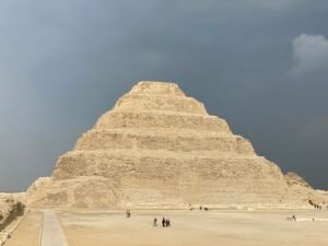 Step Pyramid of Djoser rising above the open court at Saqqara beneath dark storm clouds