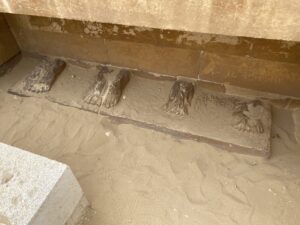 Four surviving pairs of carved statue feet on a limestone base in the Heb-Sed Court of Djoser’s Step Pyramid complex at Saqqara, Egypt