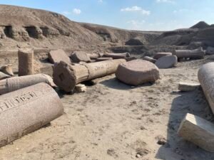Fallen inscribed granite columns and large stone blocks scattered across the archaeological site of Tanis