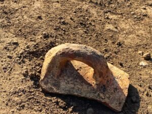 Large curved ancient pottery handle fragment lying on sandy ground at the archaeological site of Tanis