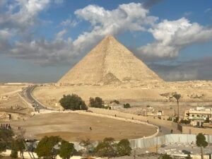 Great Pyramid of Khufu rising above the Giza Plateau beneath large white clouds