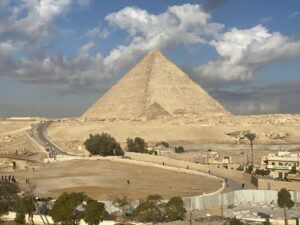 Great Pyramid of Khufu rising above the Giza Plateau beneath large white clouds