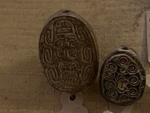 Two ancient Egyptian oval scaraboid or seal amulets shown from their engraved undersides with symbolic and geometric designs in the Egyptian Museum in Cairo
