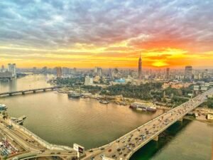 Golden sunset over Cairo with the Nile River, bridges, riverboats, city buildings, and Cairo Tower