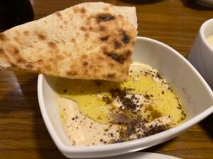 Bowl of creamy hummus topped with olive oil and spices served with flatbread at an Egyptian restaurant