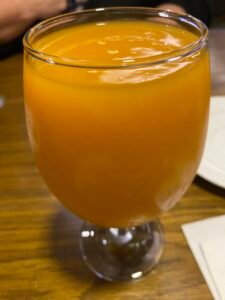 Glass of thick orange mango juice served at a restaurant table in Egypt