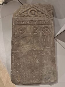 Carved Coptic funerary stela with Greek inscription, central cross, circular motifs and triangular pediment displayed at the Coptic Museum in Cairo