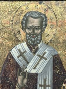 Coptic Museum icon of a haloed bishop saint with gray beard, cross-marked episcopal vestments and raised blessing hand against a gilded ornamental background