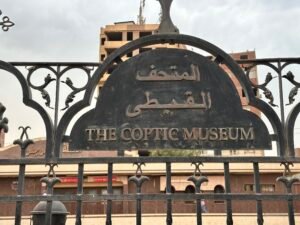 Decorative iron entrance gate sign reading The Coptic Museum in Arabic and English in Coptic Cairo