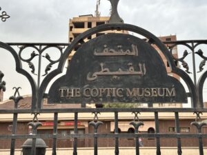 Decorative iron entrance gate sign reading The Coptic Museum in Arabic and English in Coptic Cairo