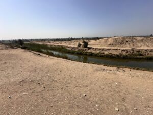Narrow irrigation canal running between sandy desert banks and cultivated vegetation near Lahun, Egypt