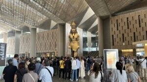 Grand Egyptian Museum Grand Hall in Giza with visitors gathered around the 11.35-meter granite colossus of Ramesses II