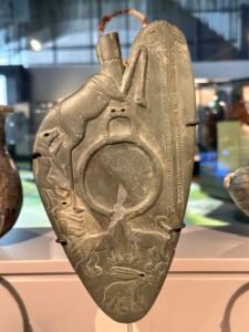 Naqada III greywacke ceremonial cosmetic palette GEM 32535 from Minshat Ezzat, carved with pursuing animals around a circular grinding recess at the Grand Egyptian Museum in Giza