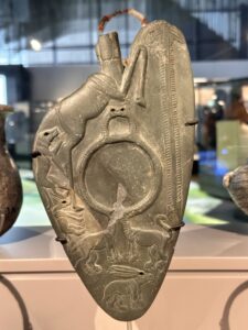 Naqada III greywacke ceremonial cosmetic palette GEM 32535 from Minshat Ezzat, carved with pursuing animals around a circular grinding recess at the Grand Egyptian Museum in Giza