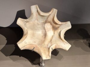 Ancient Egyptian six-lobed flower-shaped hard-stone vessel with deep curved recesses and a shallow central basin, displayed at the Grand Egyptian Museum in Giza