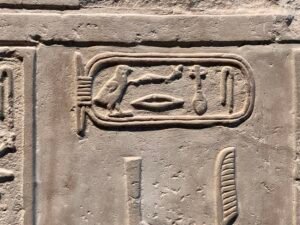 Close-up of a carved royal cartouche and hieroglyphs on an ancient Egyptian stone relief
