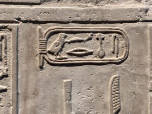 Close-up of a royal cartouche carved on an ancient Egyptian stone monument displayed beside Amenhotep III material in the Grand Egyptian Museum in Giza