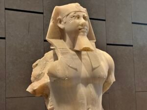Fragmentary limestone statue of an Egyptian pharaoh wearing a nemes headdress and false beard at the Grand Egyptian Museum
