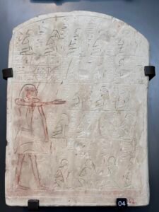 Painted limestone Middle Kingdom stela from Abydos with hieroglyphs and a standing figure, displayed at the Grand Egyptian Museum in Giza