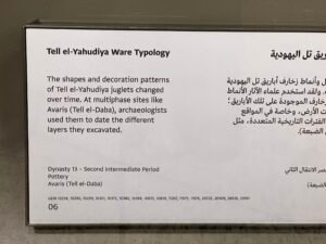 Grand Egyptian Museum panel explaining Dynasty 13–Second Intermediate Period Tell el-Yahudiya Ware from Avaris and how changing juglet shapes and decoration help date archaeological layers