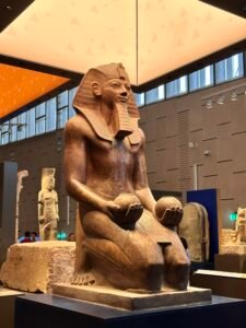 Colossal seated statue of Pharaoh Amenhotep II holding two rounded offering vessels, Dynasty 18, from Karnak and displayed at the Grand Egyptian Museum in Giza