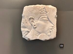 Limestone relief fragment showing an Amarna-period royal profile with elongated facial features and a uraeus