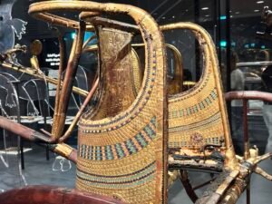 Gilded ceremonial state chariot of Tutankhamun from tomb KV62 with blue, red and gold inlay, displayed in the Tutankhamun Galleries at the Grand Egyptian Museum in Giza