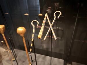 Group of Tutankhamun’s ceremonial walking sticks and staffs from tomb KV62, including striped hooked canes and knobbed staffs, displayed at the Grand Egyptian Museum in Giza