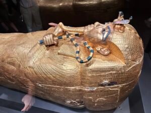 Gilded outer coffin of Pharaoh Tutankhamun, GEM 7590, with crossed crook and flail and protective royal insignia in the Grand Egyptian Museum in Giza