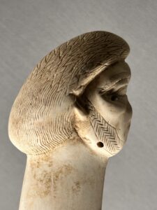 Ivory hairpin JE 46407 carved with a human head and detailed patterned wig, found in Giza tomb G 8978 associated with Queen Khamerernebty II and displayed in the Egyptian Museum in Cairo
