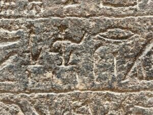 Close-up of deeply weathered ancient Egyptian hieroglyphs carved into rough stone