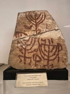 Roman-period limestone Jewish stela painted with three menorahs and Hebrew and Greek inscriptions, displayed at the Egyptian Museum in Cairo