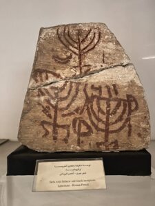 Roman-period limestone Jewish stela painted with three menorahs and Hebrew and Greek inscriptions, displayed at the Egyptian Museum in Cairo