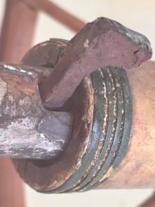 Ancient Egyptian wooden chariot axle entering a wheel hub with surviving green binding bands and a securing peg, Egyptian Museum in Cairo
