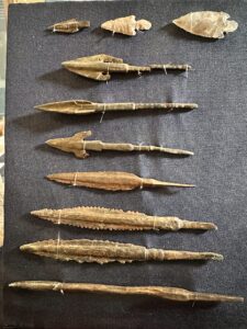 Museum display of ancient Egyptian flint arrowheads and copper-alloy spear or arrow points, including barbed and serrated forms, Egyptian Museum in Cairo