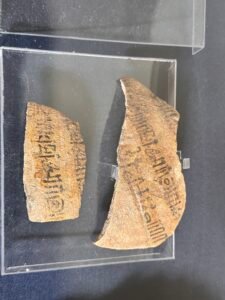 Two pottery ostraca written in black Coptic ink on reused ceramic sherds, displayed at the Egyptian Museum in Cairo