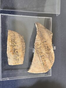 Two pottery ostraca written in black Coptic ink on reused ceramic sherds, displayed at the Egyptian Museum in Cairo