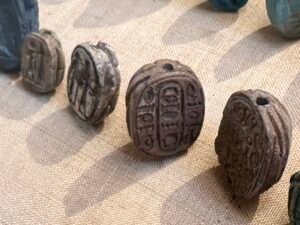 Several small ancient Egyptian scarab-shaped seals with carved hieroglyphic designs on their undersides