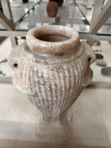 Pale hard-stone jar with deep vertical fluting, broad rim and two pierced lug handles, a Predynastic to Early Dynastic vessel type at the Egyptian Museum in Cairo