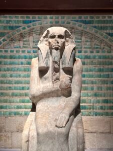 Life-size painted limestone statue of Pharaoh Djoser, JE 49158, seated in a jubilee cloak before blue faience tiles from his Step Pyramid complex at Saqqara, Egyptian Museum in Cairo