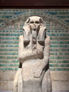 Life-size painted limestone statue of Pharaoh Djoser, JE 49158, seated in a jubilee cloak before blue faience tiles from his Step Pyramid complex at Saqqara, Egyptian Museum in Cairo